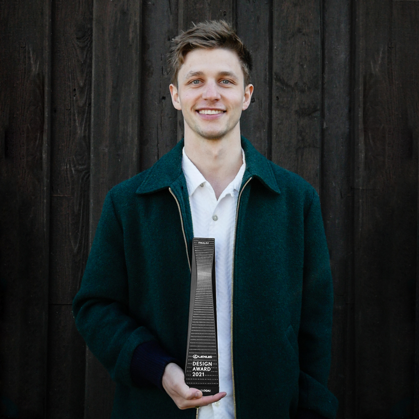 Henry Glogau stands holding his Lexus Design Award winning trophy 2021.