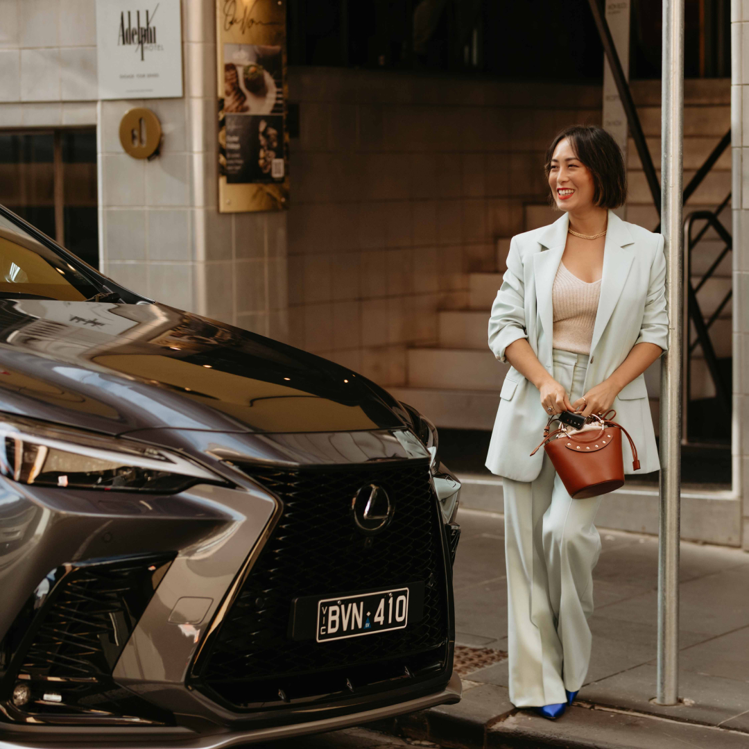 Melissa Leong leans against a pole next to a Lexus NX