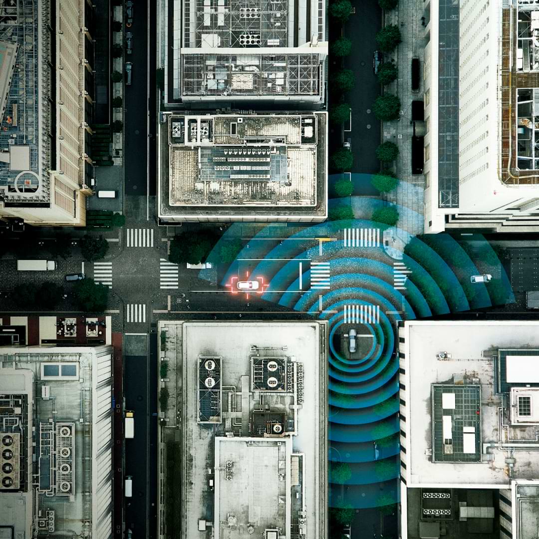 Aerial view of a city intersection showing a Lexus vehicle with visual graphics representing Front Cross Traffic Alert detection.