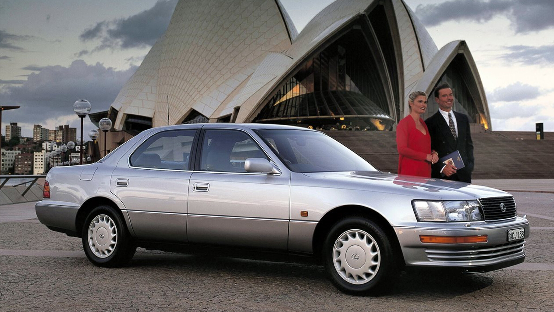 Silver Lexus LS 400 in 1990, parked next to a woman and man in front of the Sydney Opera House