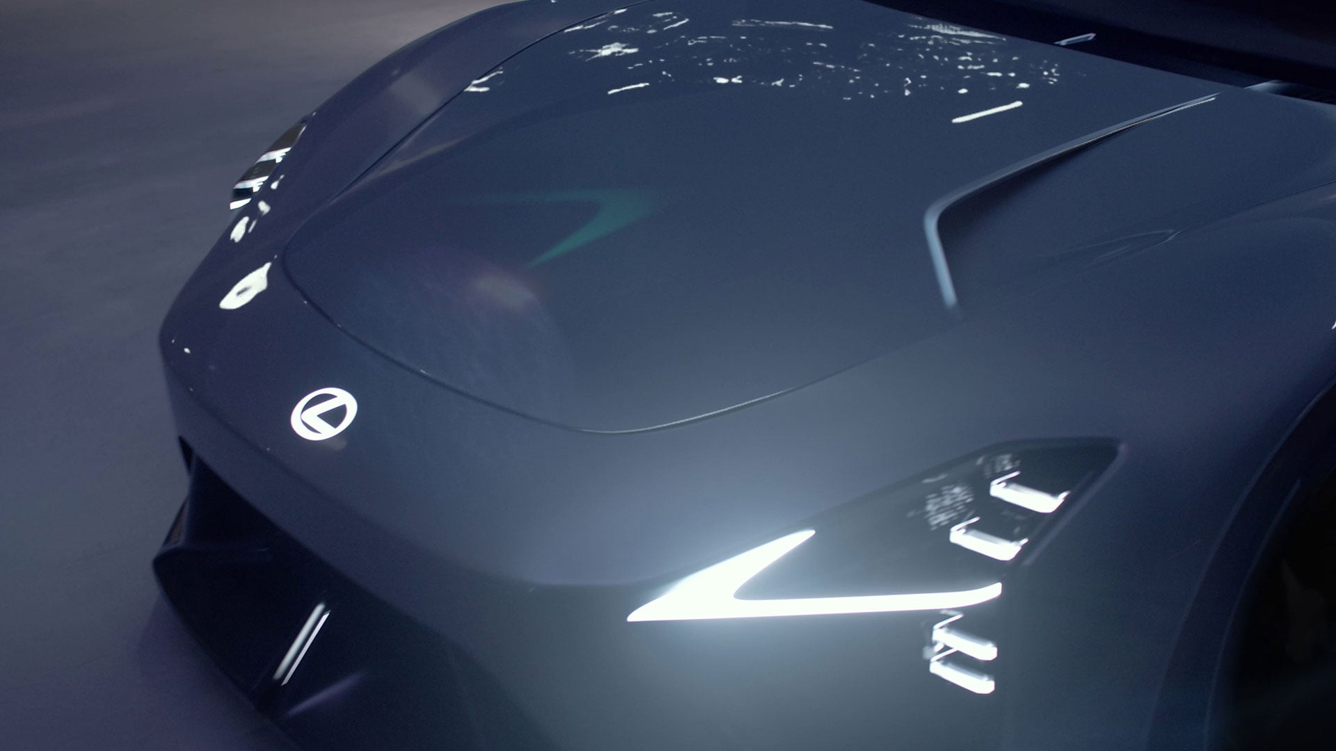 Dark grey Lexus LFA Concept BEV sports car front detail showing illuminated headlights and sculpted bonnet